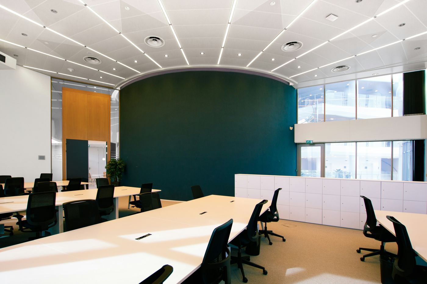 An empty modern conference room with tables, chairs and a green wall